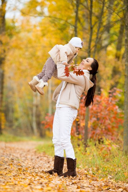 Menina e a mãe brincando no parque outono.