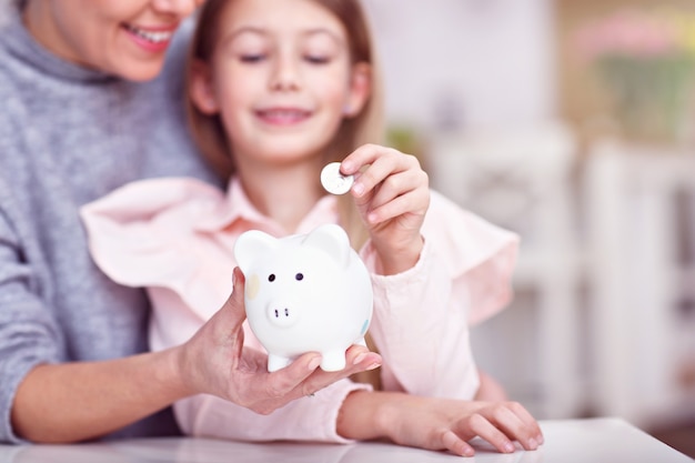 menina e a mãe dela com o cofrinho sentado à mesa