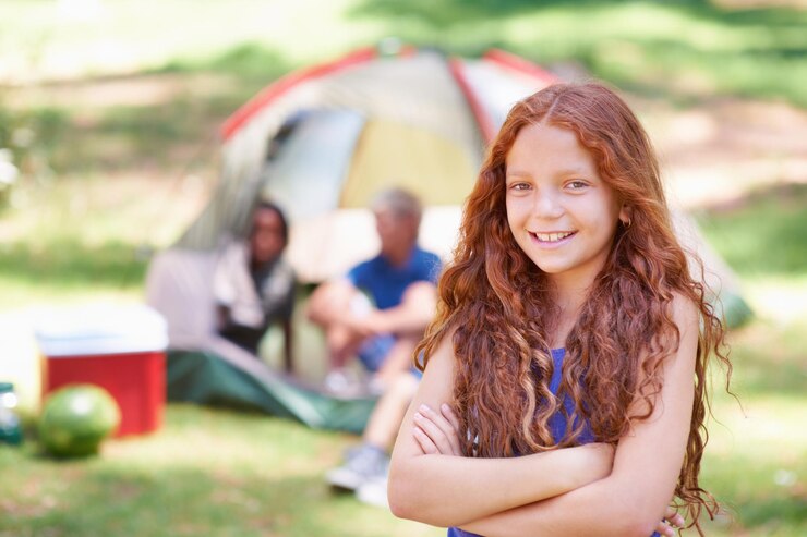 Foto menina e braços cruzados sorriem no acampamento de verão e na natureza com diversão ao ar livre para jovens em retrato criança no acampamento no parque para aventura e férias, infância e recreação com felicidade