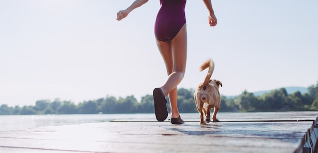 Foto menina e cachorro correndo juntos na doca do rio