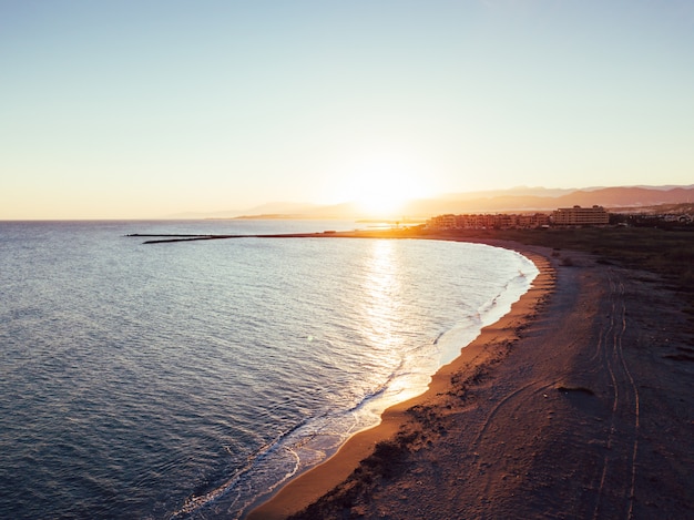 Menina e cachorro na praia ao pôr do sol, vistas aéreas