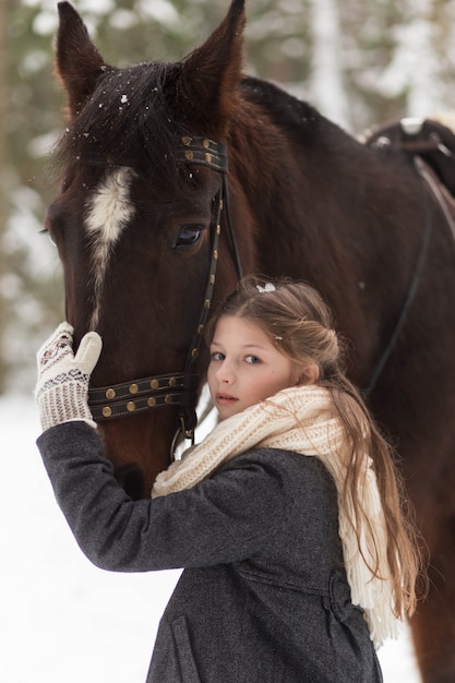 Menina e cavalo marrom no inverno na natureza