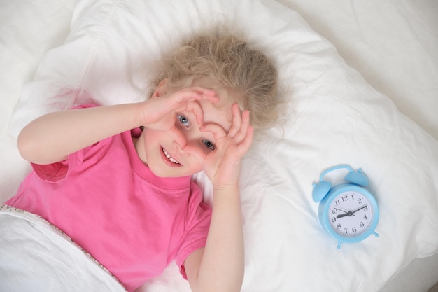 Menina e despertador na cama