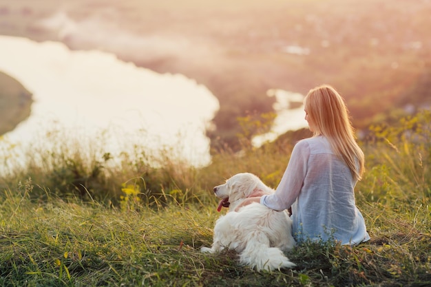 menina e golden retriever sentam-se juntos e apreciam a vista do rio