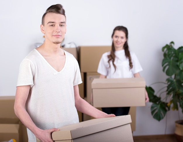 Menina e homem carregam caixas em um novo apartamento.