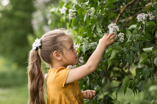 Menina e lilás flores no jardim no verão