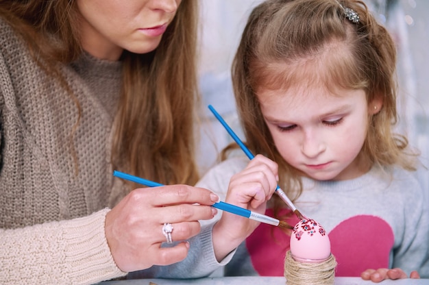 Menina e mãe pintando ovos de Páscoa