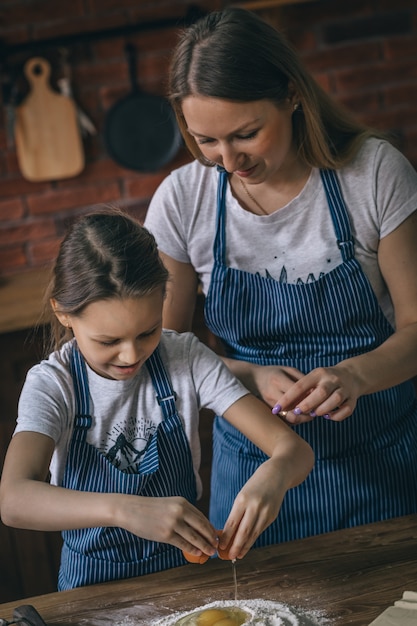 Menina e mãe quebrando ovos para farinha