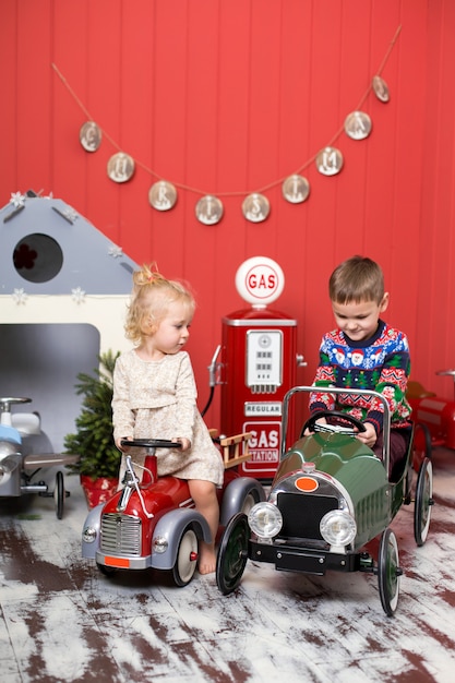 Menina e menino bonito brincam e andam em carros de brinquedo. Infância feliz