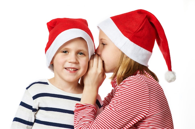 Menina e menino com chapéu de Papai Noel