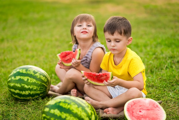 Menina e menino com um pedaço de melancia nas mãos