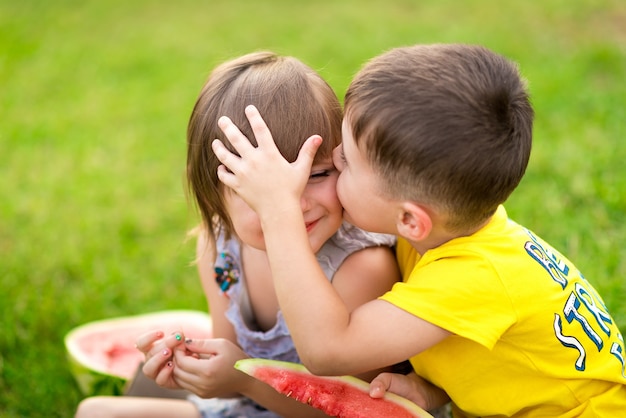 Menina e menino com um pedaço de melancia nas mãos