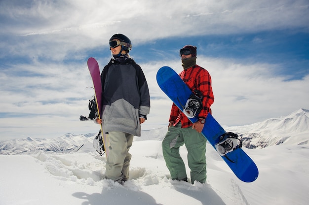 Menina e menino em pé nas montanhas com pranchas de snowboard