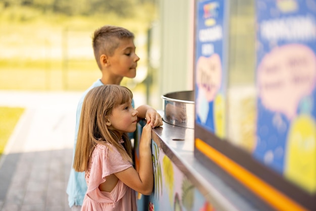 Menina e menino esperando por um algodão doce no parque de diversões