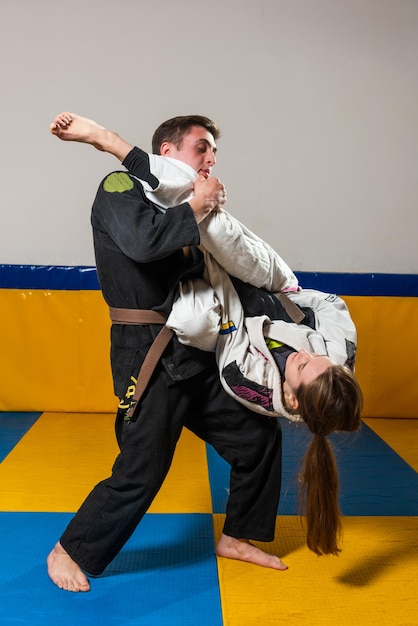 Foto menina e menino praticam jiu jitsu brasileiro na academia