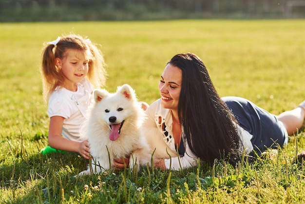 Foto menina e mulher deitada na grama com seu cachorro fofo