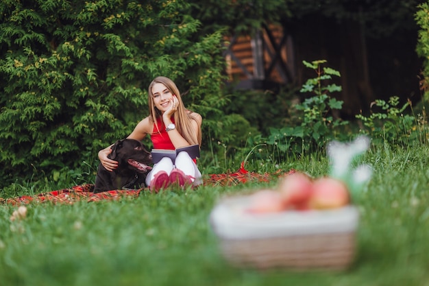 Menina e o cachorro dela sentado no jardim.