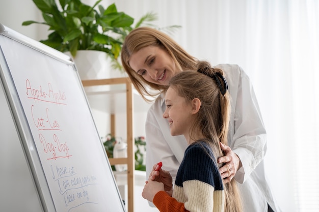 Menina e professora sorridente de tiro médio