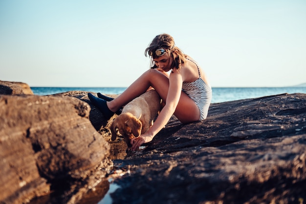 Menina e seu cachorro explorando a praia rochosa