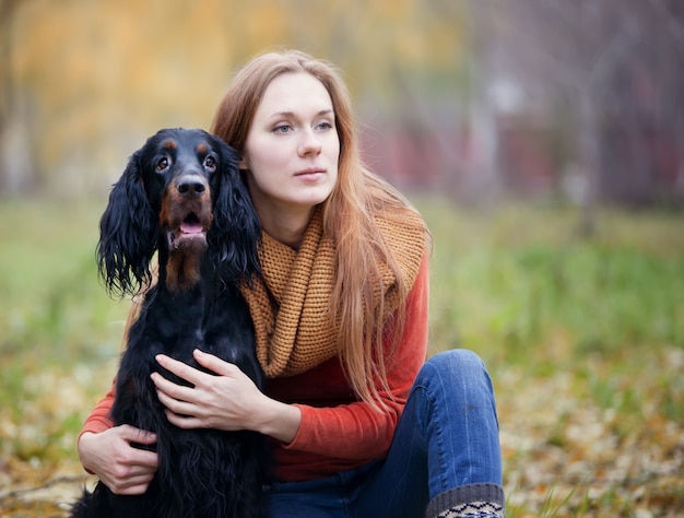 Menina e seu cão gordon setter no parque outono