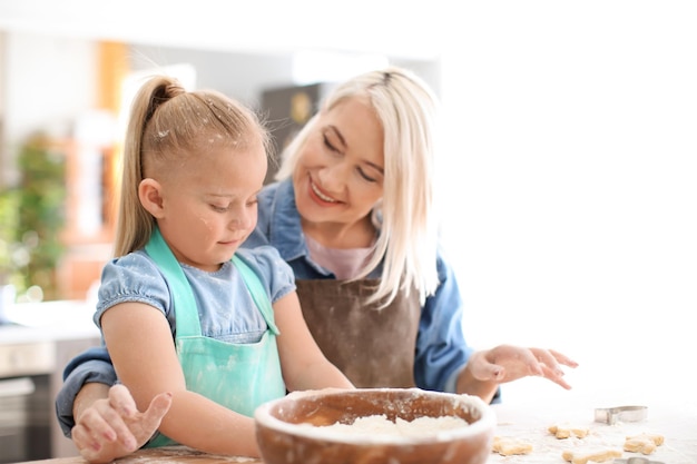 Menina e sua avó com farinha e massa de biscoito na mesa na cozinha