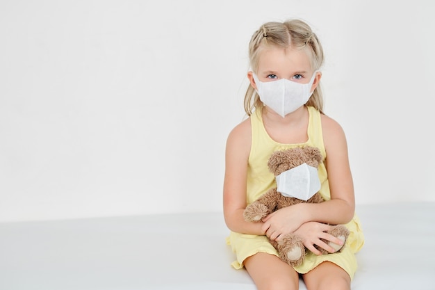 Menina e ursinho de pelúcia com máscaras médicas