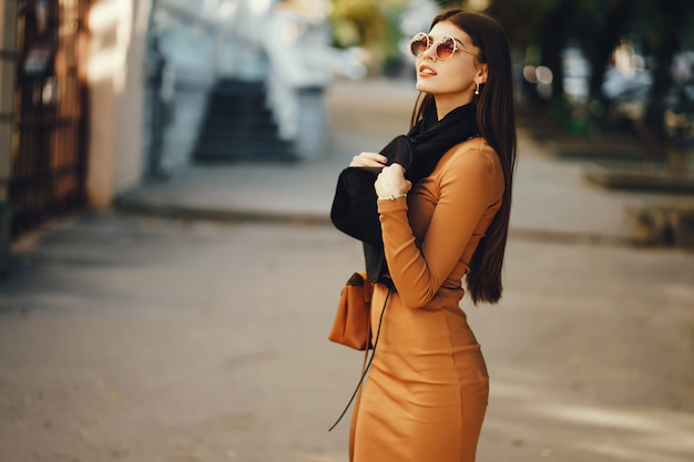 Foto menina elegante andando pela cidade em um dia quente de outono ensolarado