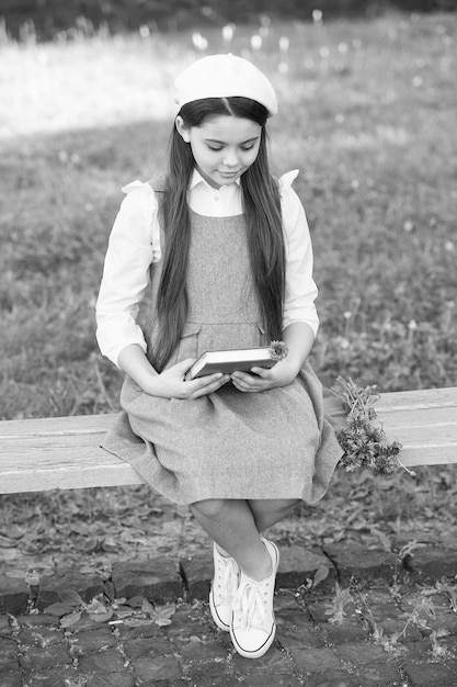 Menina elegante colegial com livro no parque lendo o conceito de poesia