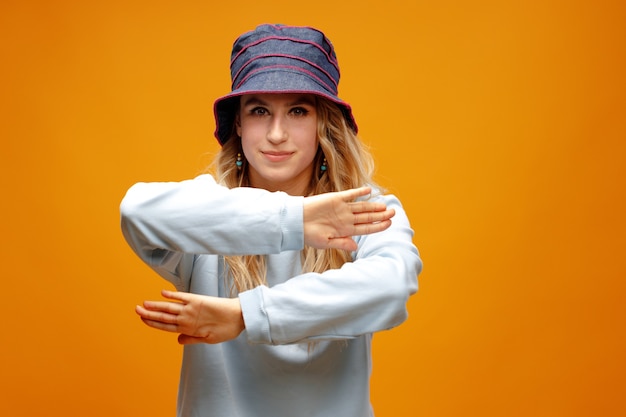 Menina elegante com chapéu-panamá dançando contra um fundo amarelo