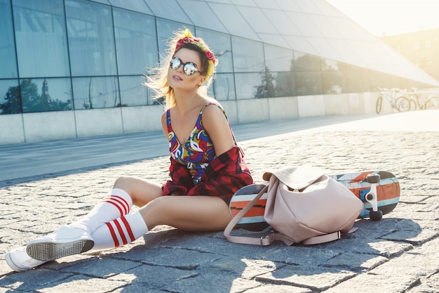 Menina elegante com um skate na rua