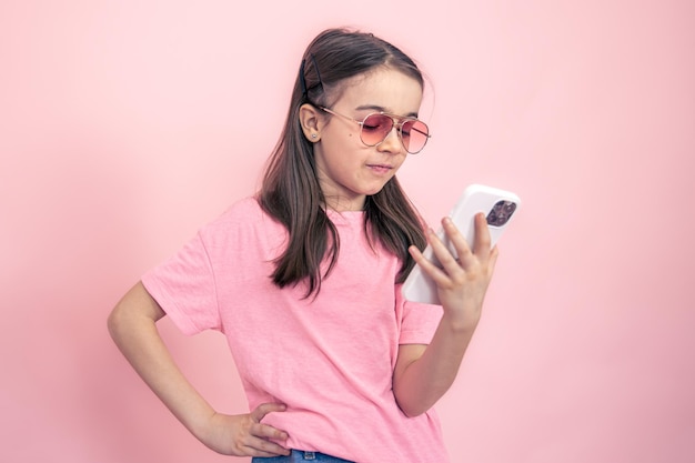 Menina elegante com um smartphone em um fundo rosa