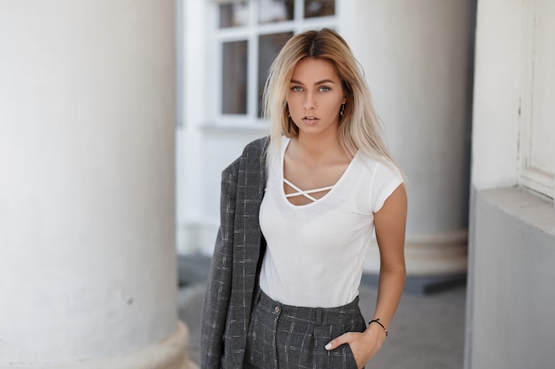 Menina elegante com uma camiseta branca estilosa e um casaco vintage cinza na rua