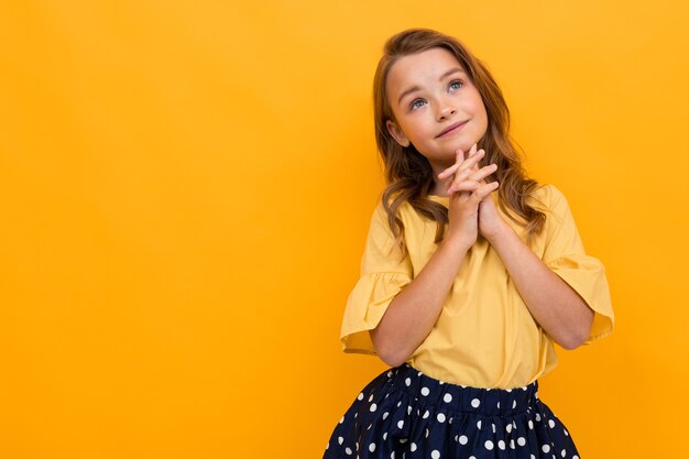 Menina elegante em uma camiseta amarela, posando como uma modelo em um fundo amarelo com cópia-espaço.