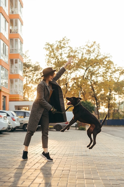 Menina elegante está treinando um cachorrinho na rua à noite
