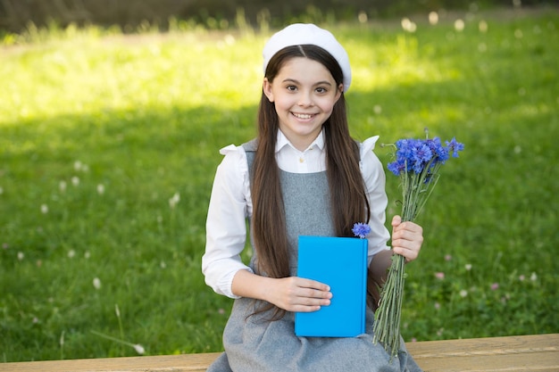 Menina elegante estudante com livro no conceito de biblioteca escolar do parque