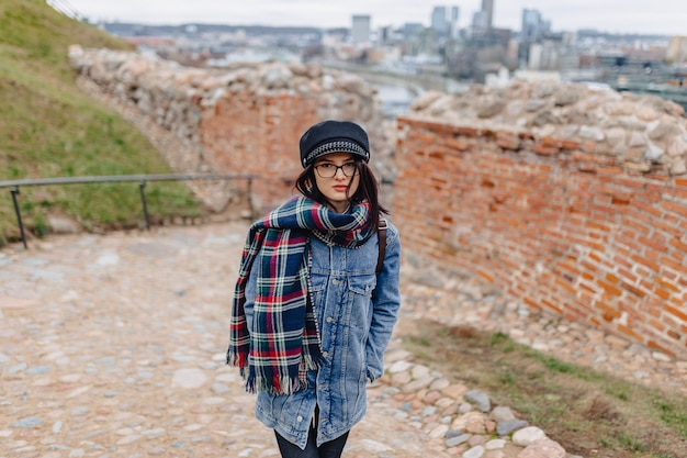 Menina elegante na caminhada de jaqueta jeans no fundo de Vilnius