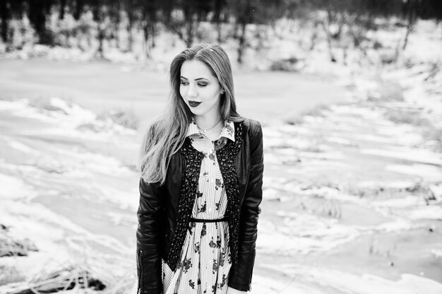 Menina elegante na jaqueta de couro em dia de inverno contra lago congelado.