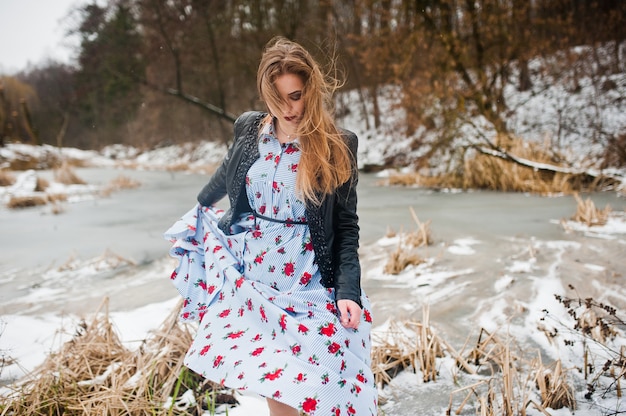 Menina elegante na jaqueta de couro em dia de inverno contra lago congelado.