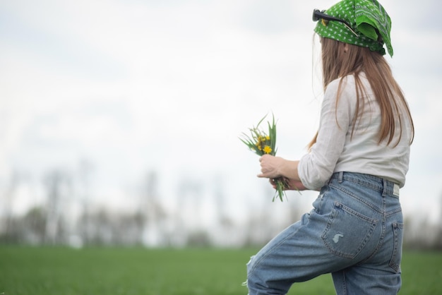 Menina elegante no estilo jeans de pé com as costas em um fundo branco ao ar livre