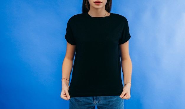 Menina elegante vestindo camiseta preta, posando no estúdio no espaço azul