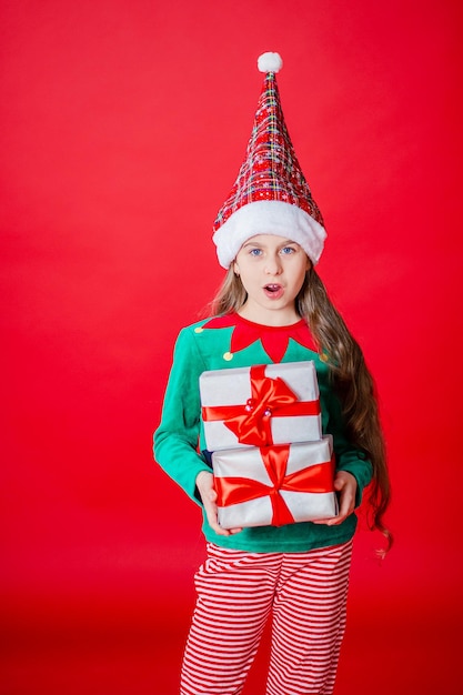 Menina elfa com presentes Ajudante do Papai Noel em um fundo de cor vermelha brilhante Copiar espaço