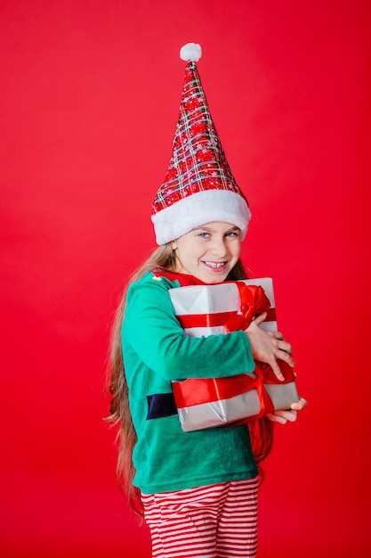 Menina elfa com presentes ajudante do papai noel em um fundo de cor vermelha brilhante copiar espaço