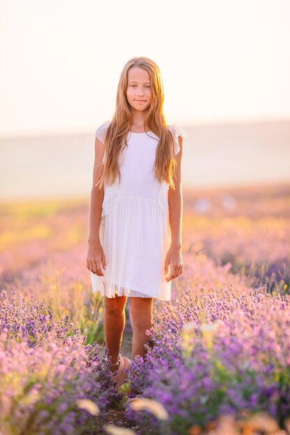 Menina em campo de flores de lavanda em vestido branco