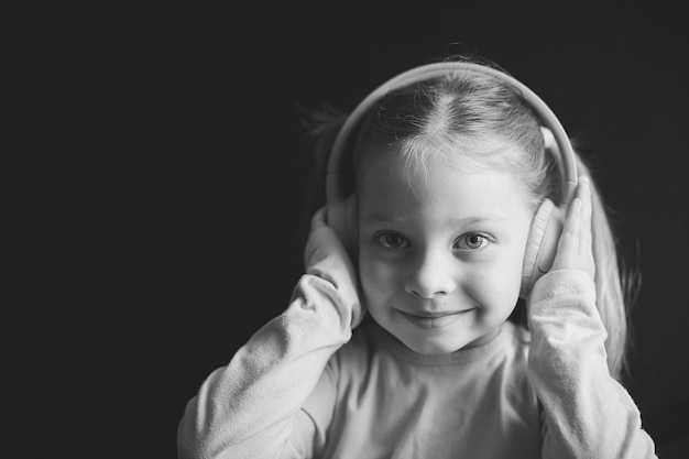 Menina em fones de ouvido ouvindo música retrato preto e branco de uma criança caucasiana