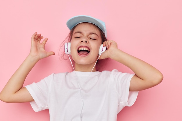 Menina em fones de ouvido posando em um fundo rosa