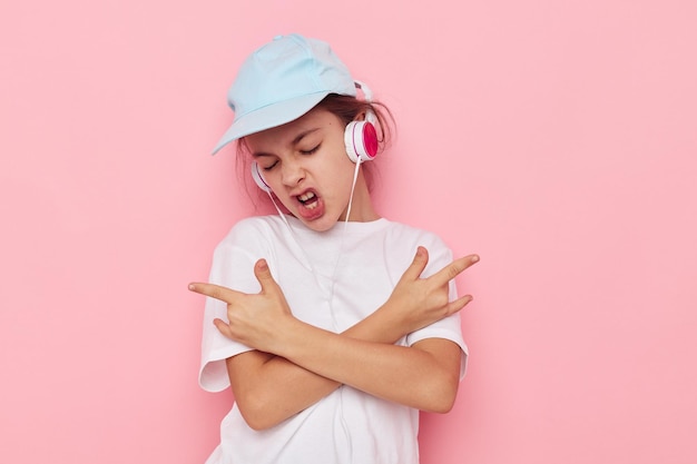 Menina em fones de ouvido posando em um fundo rosa