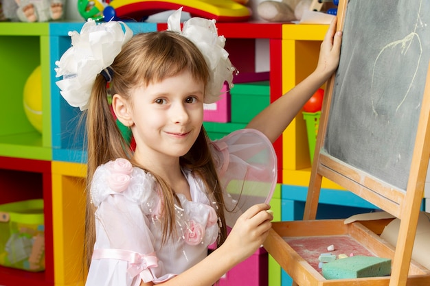 Menina em idade pré-escolar. Aluno da escola primária no quadro-negro.