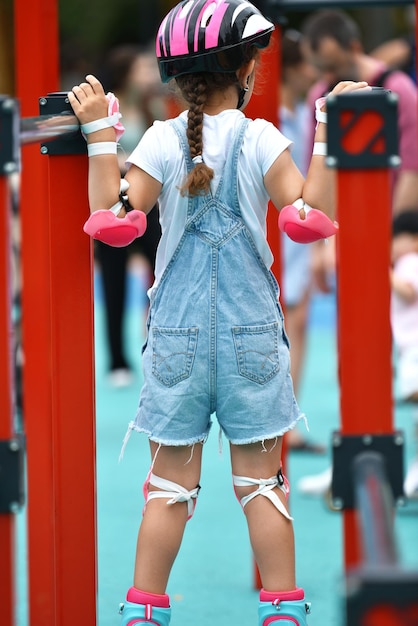 Menina em roupas de proteção capacete almofadas de joelho cotoveleiras com rolos. crossfit para crianças