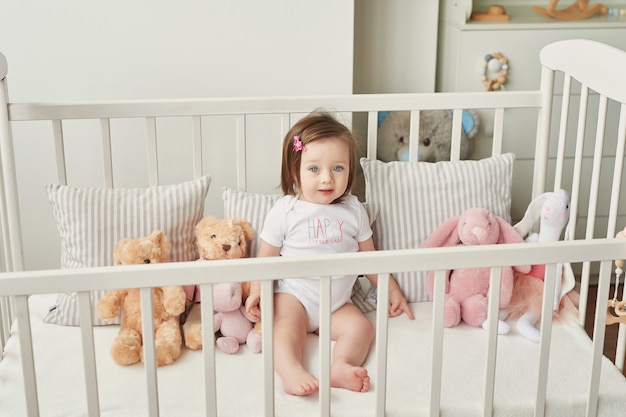 Menina em um berço com brinquedos no quarto das crianças