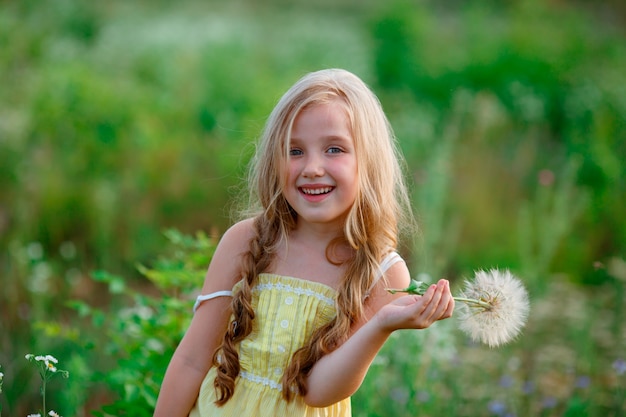 Menina em um campo com um dente de leão andando no verão